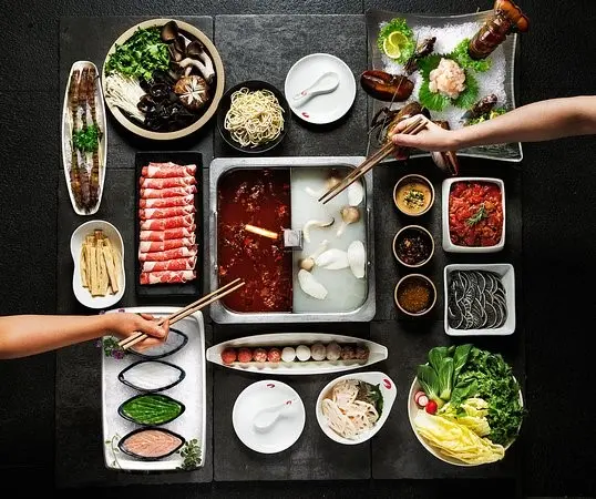 Table with steaming hot pot and fresh ingredients at Haidilao Hot Pot, Dubai Mall.